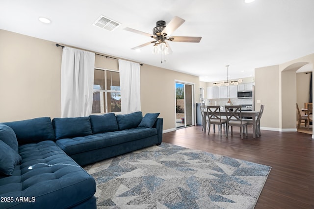 living room with dark wood-type flooring and ceiling fan