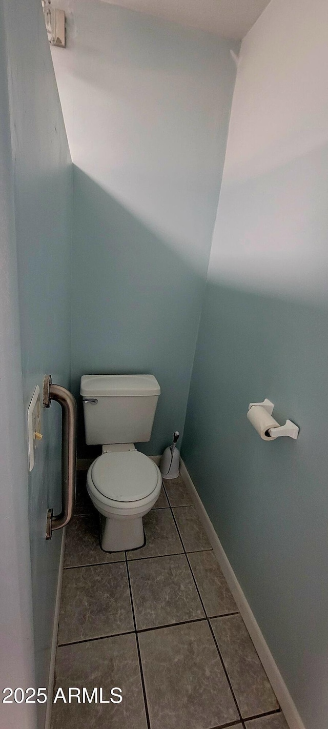 bathroom with toilet, baseboards, and tile patterned floors