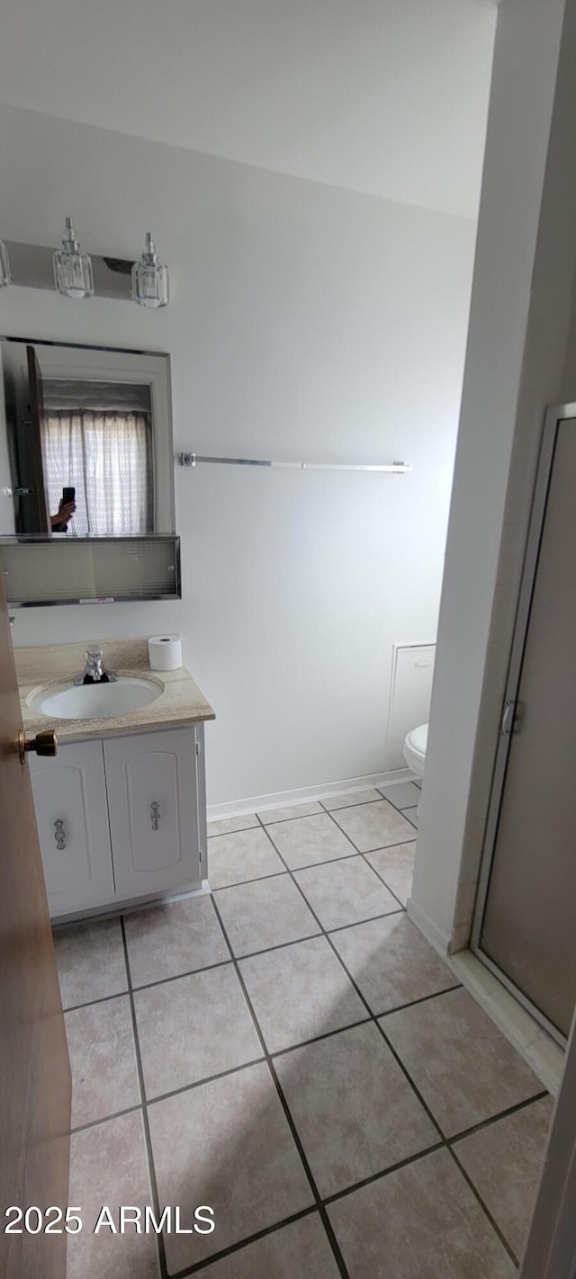 bathroom featuring toilet, vanity, baseboards, and tile patterned floors