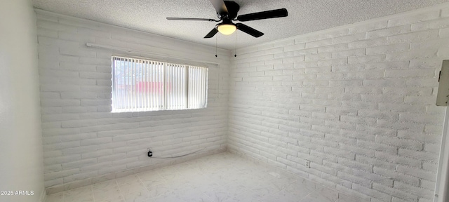 spare room with a ceiling fan, a textured ceiling, and brick wall