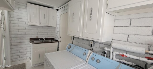 clothes washing area featuring cabinet space, washing machine and dryer, and a sink