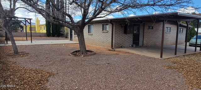 view of side of home with brick siding, a patio area, and an attached carport