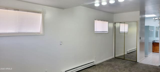 unfurnished bedroom featuring a baseboard radiator, a baseboard heating unit, carpet floors, baseboards, and a closet