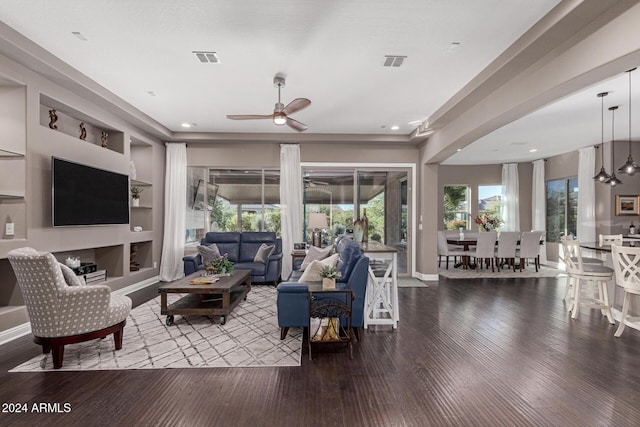 living room with wood-type flooring, built in features, and ceiling fan