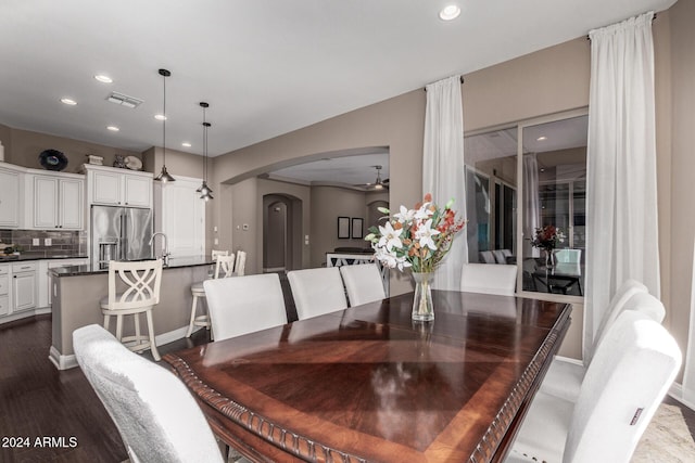 dining space with ceiling fan, sink, and dark wood-type flooring