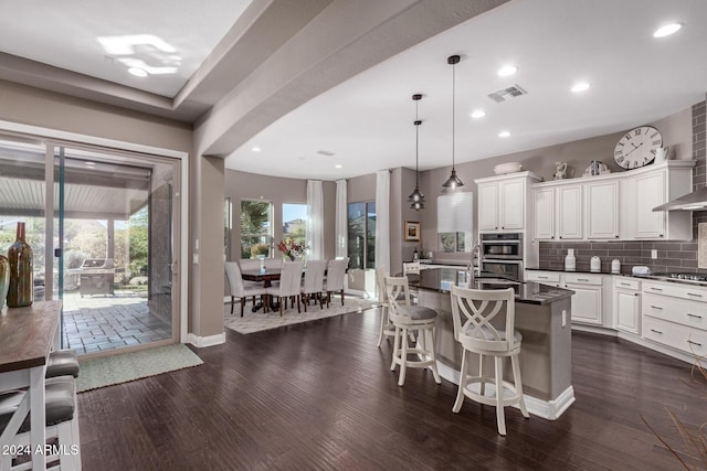 kitchen featuring pendant lighting, a breakfast bar, white cabinetry, and dark wood-type flooring