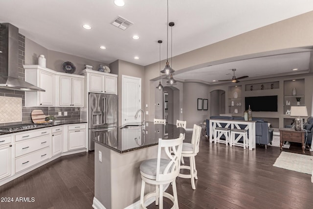 kitchen featuring stainless steel appliances, dark wood-type flooring, sink, wall chimney range hood, and pendant lighting