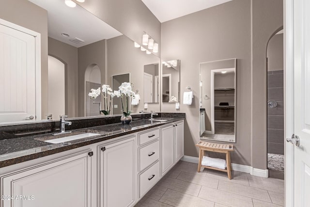 bathroom featuring tile patterned flooring, a shower, and vanity