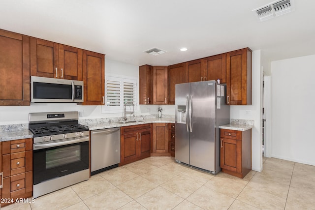 kitchen with stainless steel appliances, visible vents, a sink, and light stone countertops