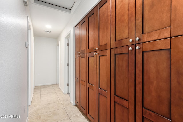 hallway featuring light tile patterned flooring, visible vents, and baseboards