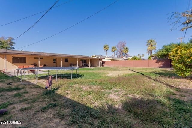 view of yard with a trampoline and fence