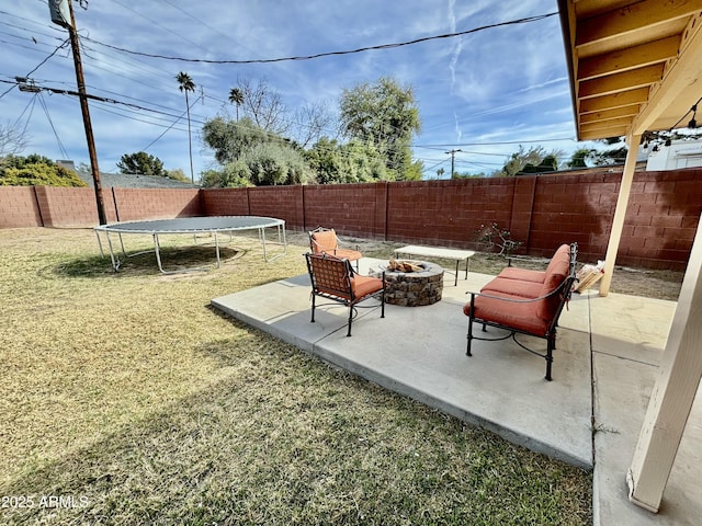 view of patio / terrace with a trampoline, a fenced backyard, and a fire pit