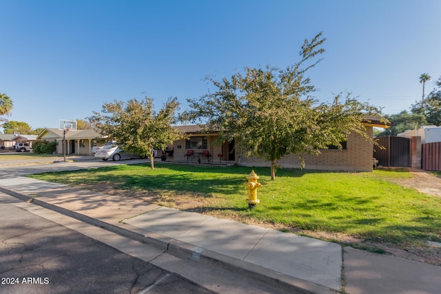 obstructed view of property with a front yard, fence, concrete driveway, and brick siding