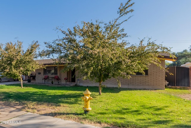 obstructed view of property featuring a front yard and brick siding