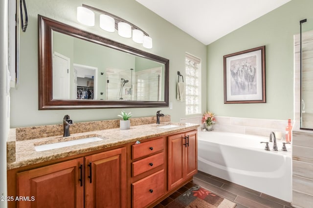 full bath featuring a walk in closet, a garden tub, a sink, and a shower stall