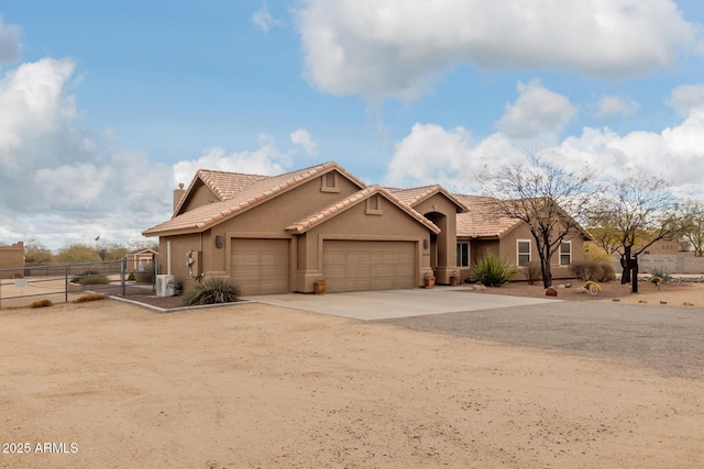 view of front of home with a tile roof, dirt driveway, stucco siding, an attached garage, and fence