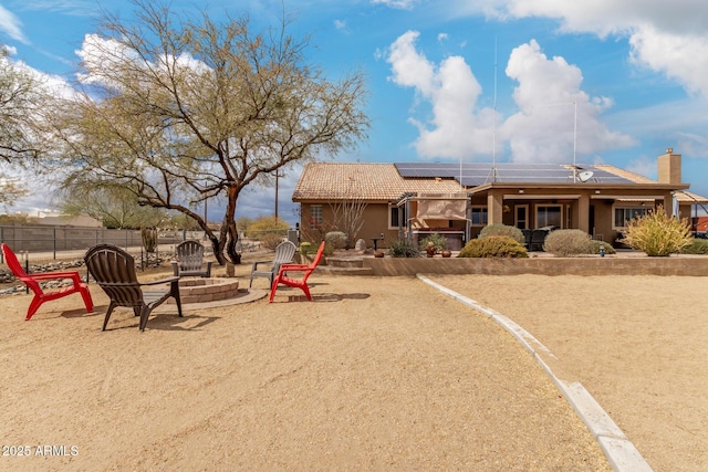 exterior space with a tile roof, an outdoor fire pit, roof mounted solar panels, and a patio area