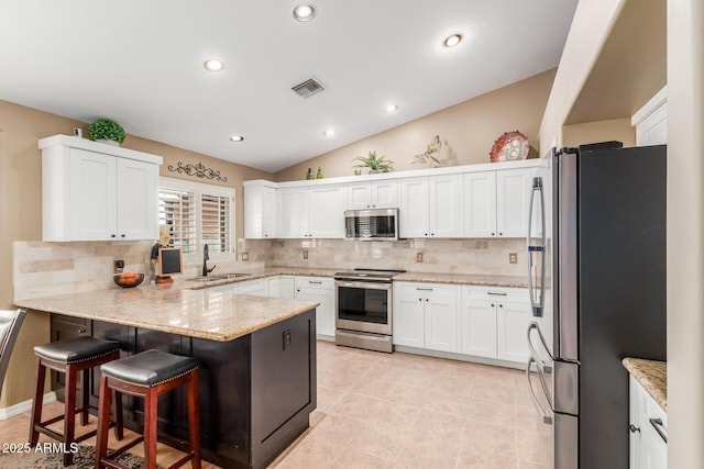 kitchen with visible vents, appliances with stainless steel finishes, light stone counters, a peninsula, and a sink