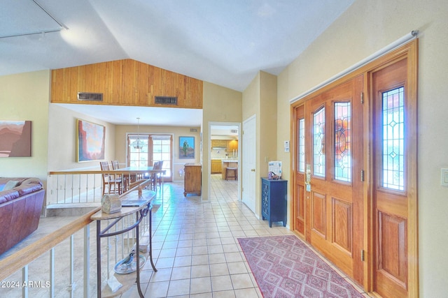 foyer entrance with light tile patterned floors and vaulted ceiling