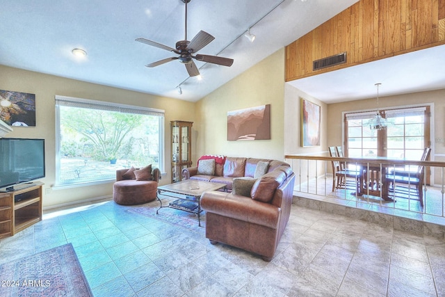 living room featuring vaulted ceiling, track lighting, and ceiling fan with notable chandelier