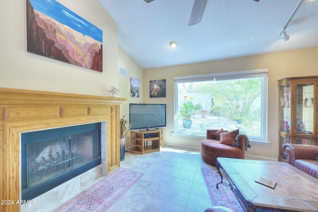 living room with a tiled fireplace, vaulted ceiling, and track lighting