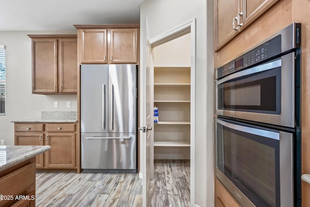 1344 N Claiborne, Mesa, AZ 85205 - kitchen featuring appliances with stainless steel finishes, light stone countertops, light wood-type flooring, and brown cabinets