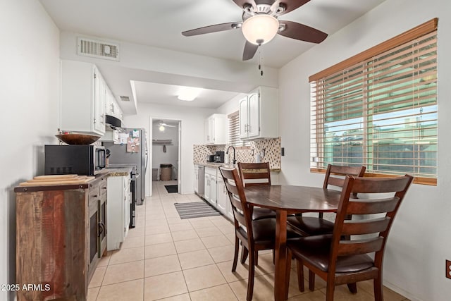 tiled dining space featuring ceiling fan and sink