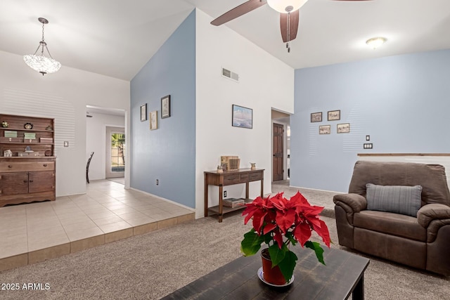 carpeted living room featuring vaulted ceiling and ceiling fan with notable chandelier