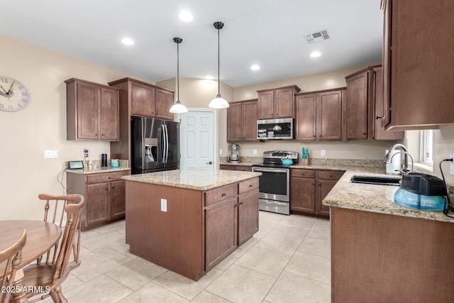 kitchen featuring visible vents, a sink, light stone counters, a kitchen island, and appliances with stainless steel finishes