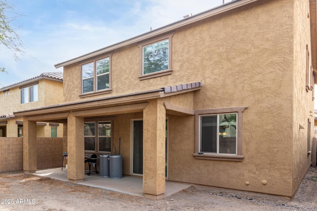 back of property featuring stucco siding, fence, a tile roof, and a patio area