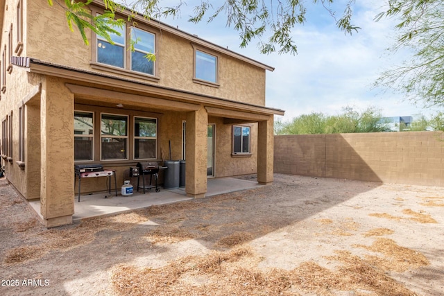 rear view of property with a patio area, stucco siding, and fence