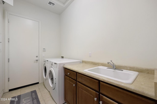 laundry area featuring separate washer and dryer, sink, light tile patterned floors, and cabinets