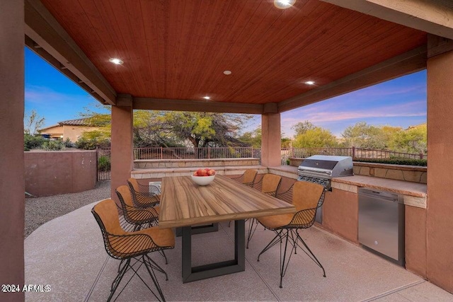 patio terrace at dusk with grilling area and an outdoor kitchen