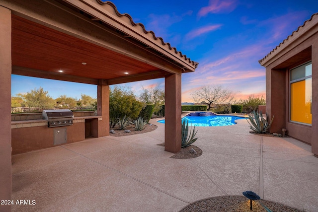 patio terrace at dusk with area for grilling and a swimming pool with hot tub