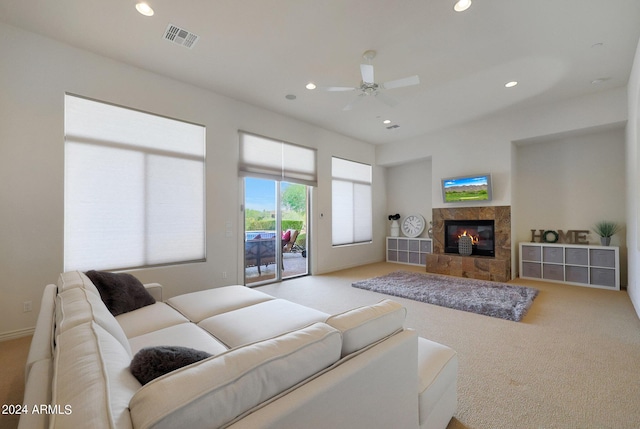 carpeted living room with ceiling fan and a fireplace