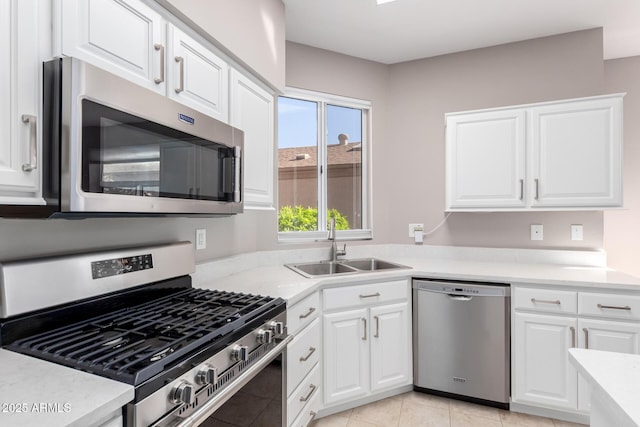 kitchen featuring appliances with stainless steel finishes, sink, light tile patterned floors, and white cabinets