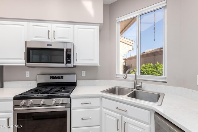 kitchen with stainless steel appliances, white cabinetry, and sink