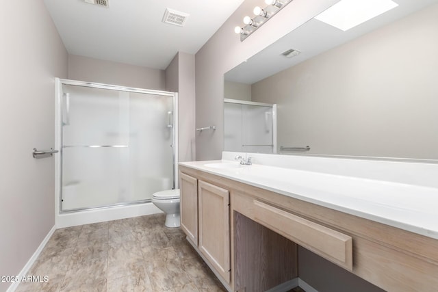 bathroom featuring vanity, a skylight, a shower with door, and toilet