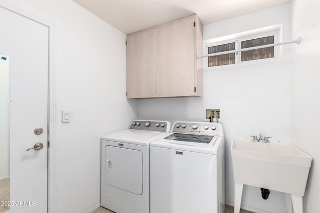 clothes washing area with cabinets, washing machine and dryer, and sink