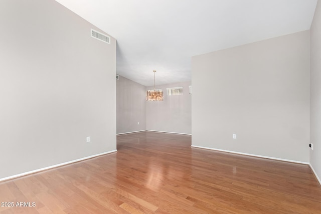 unfurnished room featuring hardwood / wood-style floors and a notable chandelier