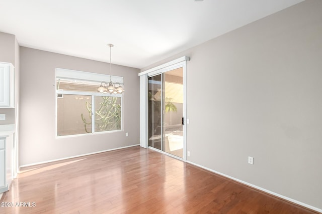 unfurnished dining area with an inviting chandelier and light hardwood / wood-style floors