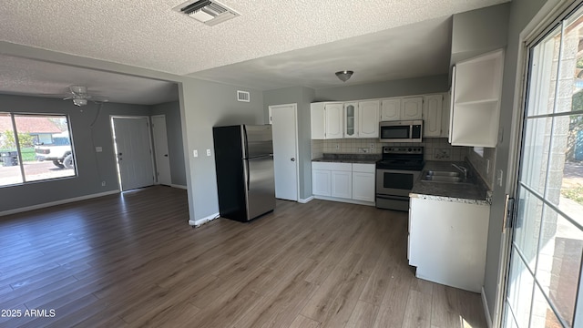 kitchen featuring wood finished floors, a sink, appliances with stainless steel finishes, white cabinetry, and visible vents