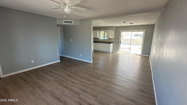 unfurnished room with a textured ceiling, a ceiling fan, baseboards, and visible vents