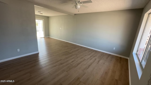 empty room with dark wood finished floors, ceiling fan, baseboards, and a textured ceiling