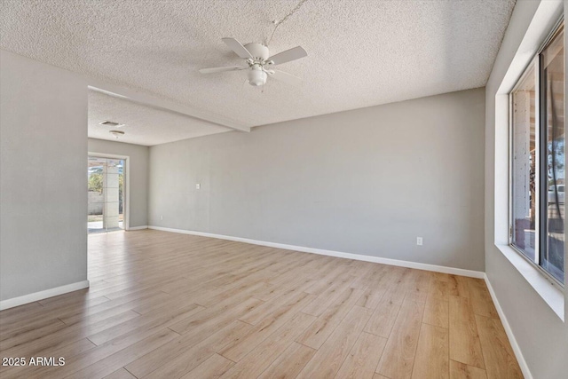 empty room featuring ceiling fan, a textured ceiling, visible vents, and light wood-style flooring