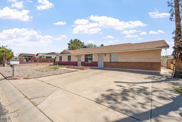 ranch-style house featuring fence and brick siding