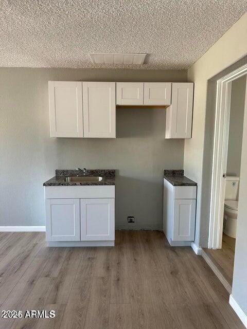 kitchen featuring white cabinetry, light hardwood / wood-style floors, and sink