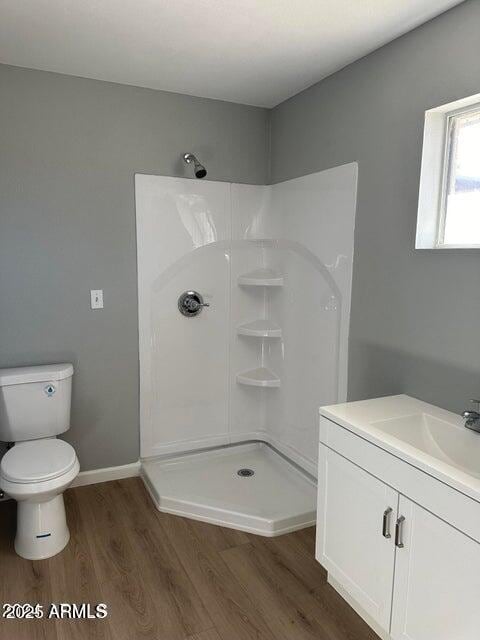 bathroom featuring vanity, toilet, wood-type flooring, and a shower