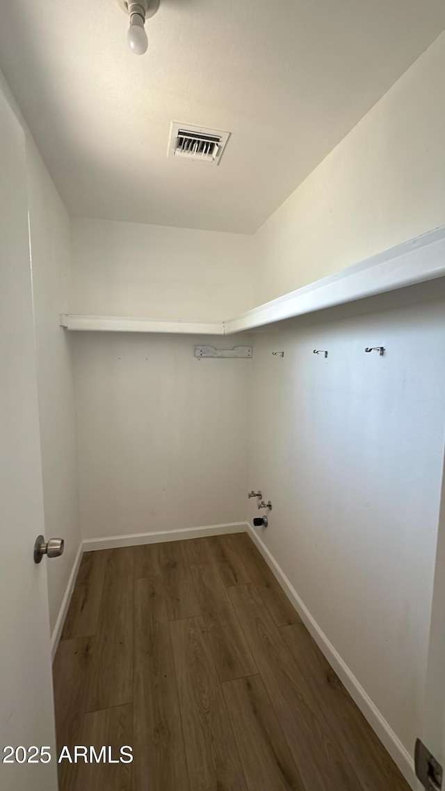 clothes washing area featuring baseboards, laundry area, wood finished floors, and visible vents