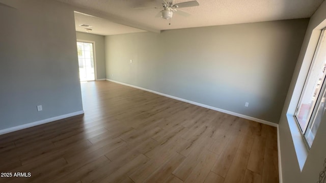 unfurnished room featuring a ceiling fan, baseboards, and dark wood-style flooring
